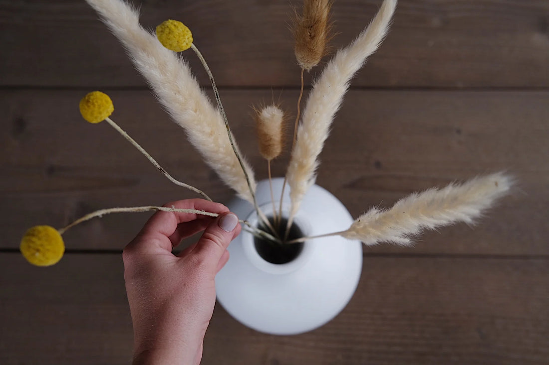 Hand putting florals into an urn