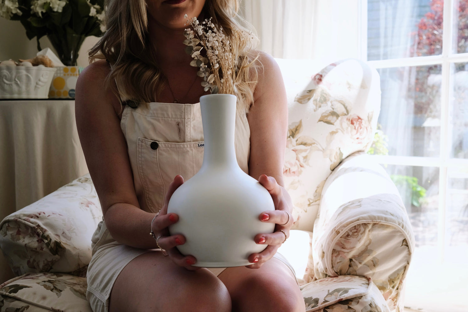 Woman holding Welkin urn in floral arm chair