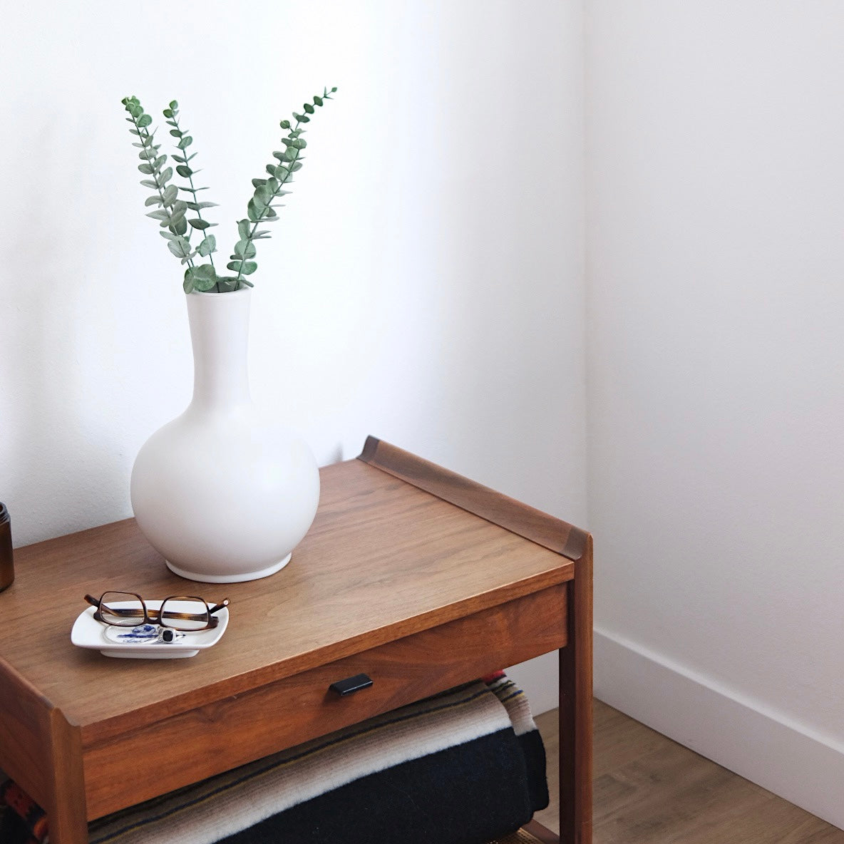 White urn vase sitting on a nightstand