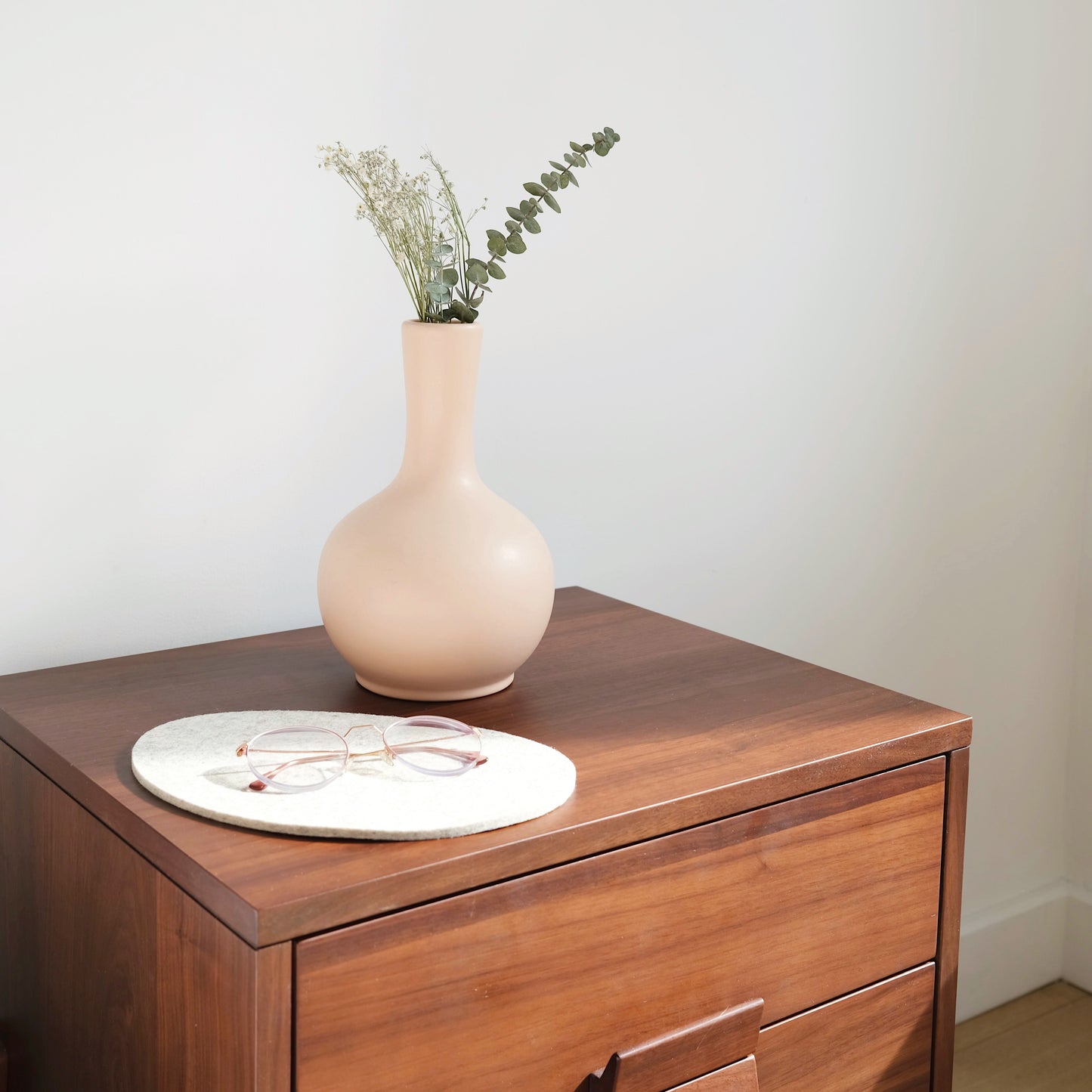 Small urn sitting on a nightstand with glasses