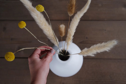 Hand putting florals into an urn