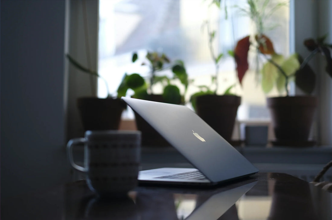 A laptop sitting on a desk with a coffee cup